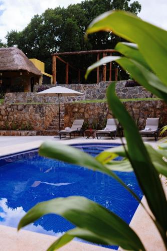 a swimming pool with two chairs and an umbrella at Hotel Rinconada del Convento in Izamal