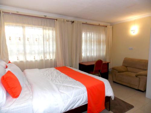 a hotel room with a bed and a chair at Axis Garden Suites 8-Bedroom Villa Near JKIA & SGR in Syokimau