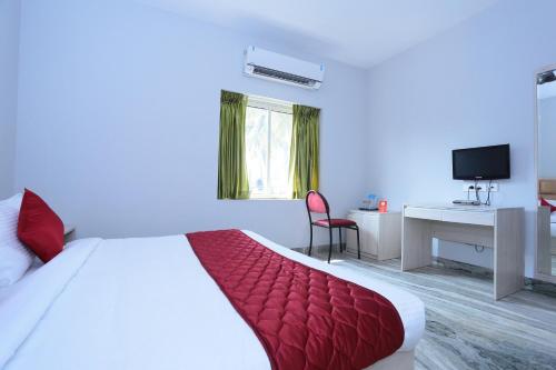 a bedroom with a bed and a desk and a television at Super Townhouse Prince Palace in Trivandrum