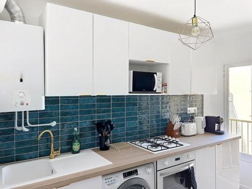 a kitchen with white cabinets and green tile on the wall at Beautiful 4 rooms sea airport in Nice