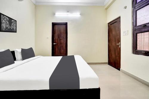 a bedroom with a white bed and a wooden door at Hotel O Mani bhai patel in Kota