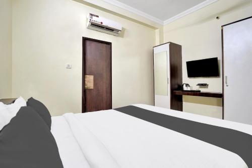 a bedroom with a white bed and a television at Hotel O Mani bhai patel in Kota