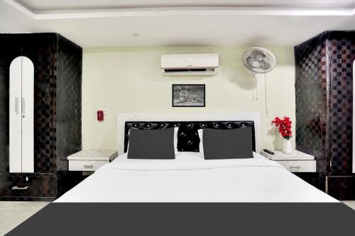 a bedroom with a large white bed with black furniture at Hotel O Mani bhai patel in Kota