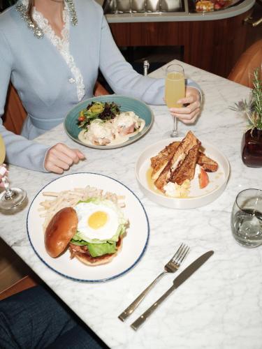 a woman sitting at a table with plates of food at The Crescent Hotel, Fort Worth in Fort Worth