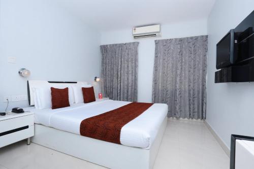 a bedroom with a large white bed and a television at Super Townhouse Malabar Illam Kochi in Cochin