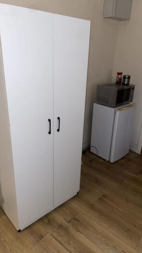 a white cabinet in a room with a microwave at Elegant En-Suite Room for a Relaxing Stay in Slough