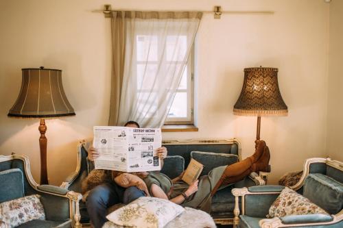 two people sitting on a couch reading a newspaper at U Květů in Milešov