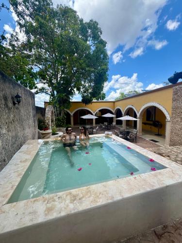 two people in the swimming pool of a house at Hotel Rinconada del Convento in Izamal