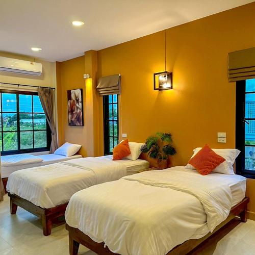 two beds in a room with yellow walls at Mimi Pool Villa Chiangmai in Chiang Mai