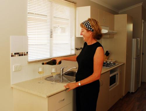 Eine Frau steht in einer Küche mit einem Glas Wein in der Unterkunft Discovery Parks - Carnarvon in Carnarvon