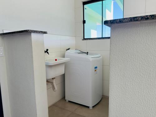 a bathroom with a sink and a washing machine at Nalevaiko- Apartamento com Varanda e Ar Condicionado in Sinop