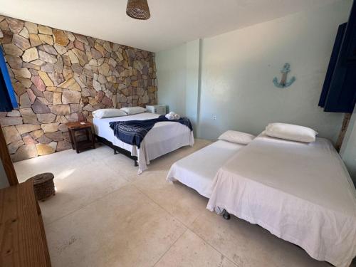 une chambre avec deux lits et un mur en pierre dans l'établissement Maraville KAI - Rooftop e Suítes confortáveis, internet e boa localização, à Barra Grande