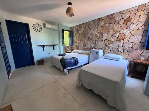 une chambre avec deux lits et un mur en pierre dans l'établissement Maraville KAI - Rooftop e Suítes confortáveis, internet e boa localização, à Barra Grande