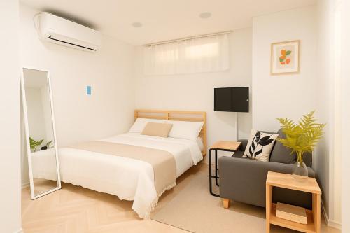 a white bedroom with a bed and a couch at Join Stay in Seoul