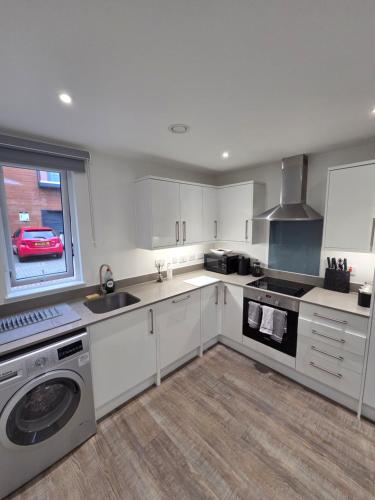 a kitchen with white cabinets and a sink and a dishwasher at City Haven, Luxury 2-Bed, 2-Bath City Centre Flat with Gym & Garden - Steps from Cruise Terminal in Southampton