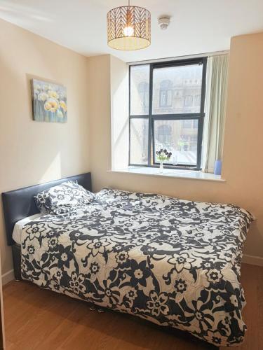 a bedroom with a bed with a black and white comforter at Double Bed Apartment Bradford City Center in Bradford