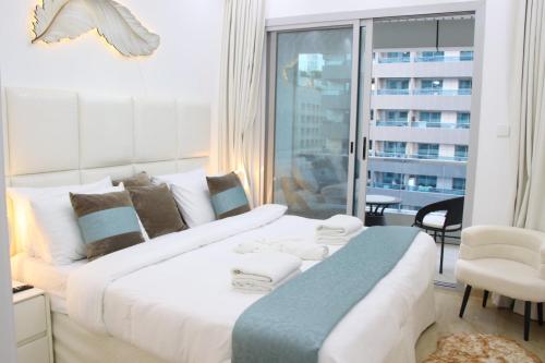 a large white bed in a room with a window at Dubai Marina 1BR with Balcony, Near Metro, Walk to JBR beach & Marina Promenade in Dubai