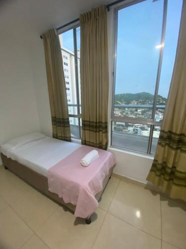 a bedroom with a bed and a large window at apartamento cerca al mar in Estación El Salto