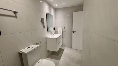 a white bathroom with a toilet and a sink at Kantara Garden Apt by TrulyCyprus in Limassol