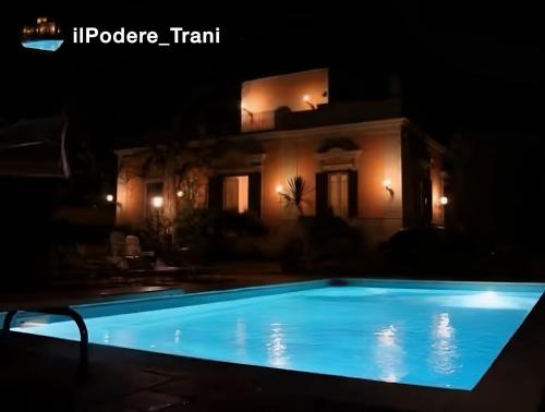 a swimming pool in front of a house at night at Il Podere in Trani