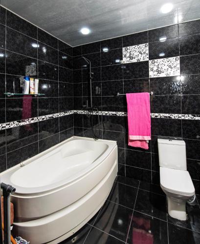 a black tiled bathroom with a tub and a toilet at Likani Verde in Borjomi
