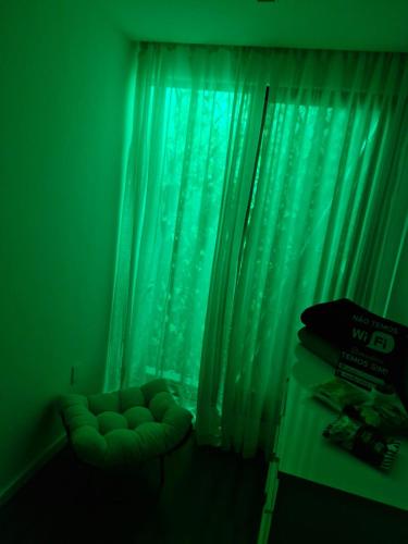a green room with a couch in front of a window at Suíte tripla com vista piscina em casa familiar de luxo em Itaipu in Niterói