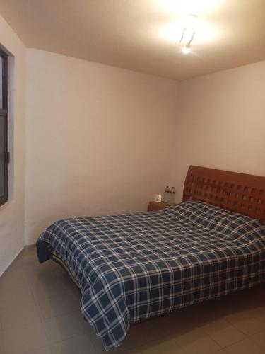 a bedroom with a bed with a blue plaid blanket at Casa Villa Real in Toluca