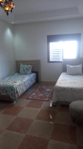 a bedroom with two beds and a window in it at khadija oulidia in Oualidia