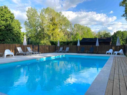 a blue swimming pool with chairs and umbrellas at Le Moulin Du Port in Saint-Georges-sur-Cher