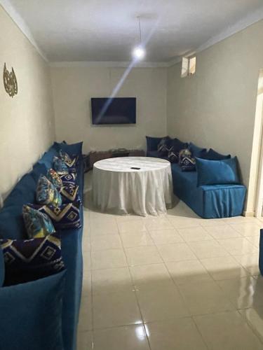 a room with a table and blue couches in a room at Havre de paix dans les montagnes in Amizmiz