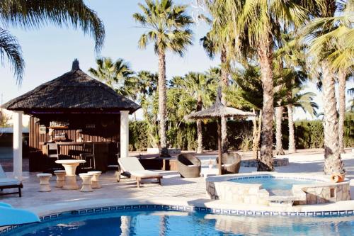 een resortzwembad met een prieel en palmbomen bij villa OLM in Ciudad Quesada