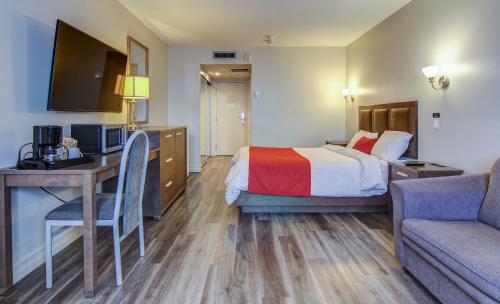 a hotel room with a bed and a desk and a couch at Chateau Roberval in Roberval