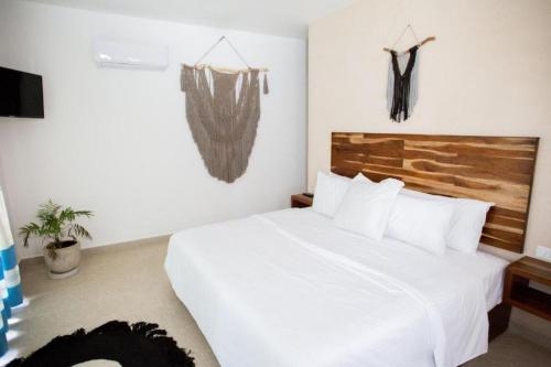 une chambre avec un lit blanc et des vêtements suspendus dans l'établissement Lagoon Boutique Hotel - Luxury Chaman experience, à Tulum