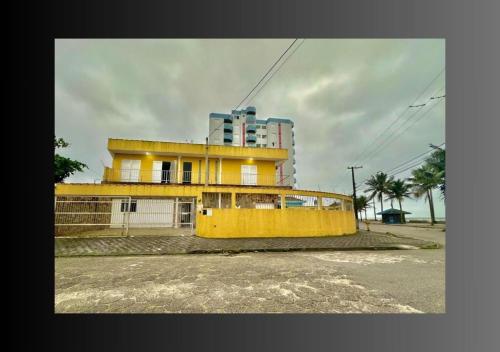 a yellow building in front of a tall building at Pousada Encanto in Mongaguá