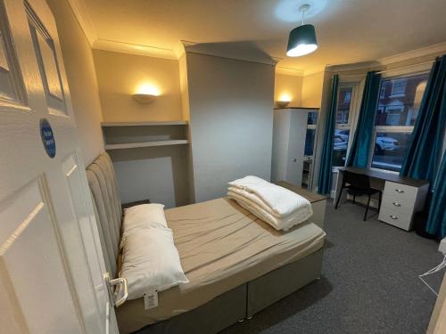 a small hospital room with a bed and a desk at 4 Double Bedroom House with Private Garden and Own Entrance in Henwick