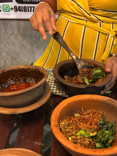 a person holding a spoon in a bowl of food at Villa Aroshina with cooking class in Galle