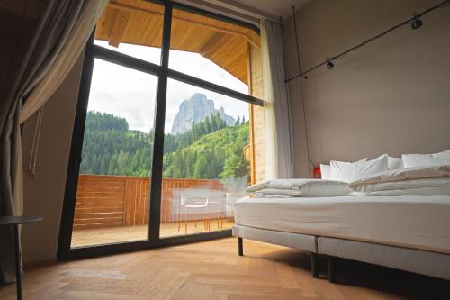 a bedroom with a bed and a large window at La Tambra - Hotel Lodge in Santa Cristina in Val Gardena