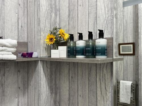 a shelf with bottles of soap and flowers on a wall at Foyers Bay Country House in Foyers