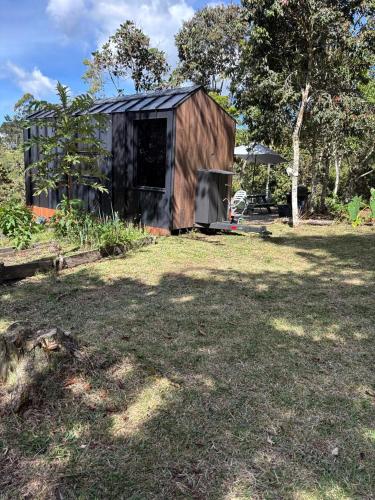 a small wooden shed in a yard with trees at Tiny House Minimalista en la Naturaleza, El Retiro in El Retiro