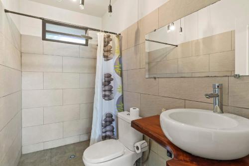 a bathroom with a sink and a toilet and a mirror at Temenino Pihiti Secluded Bungalow in Paui