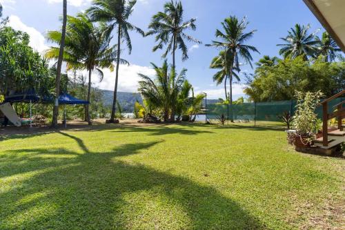 a large lawn with palm trees in the background at Temenino Pihiti Secluded Bungalow in Paui