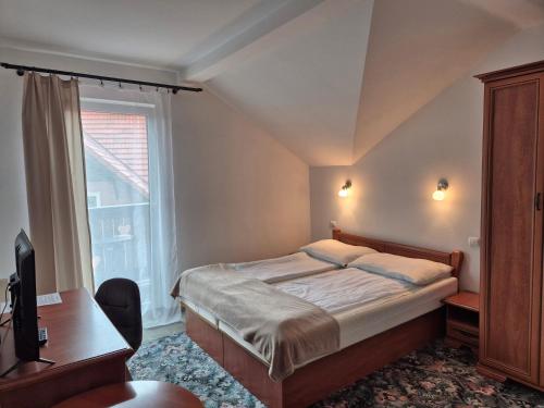 a bedroom with a bed and a desk and a window at Willa Roża Wiatrów in Karpacz