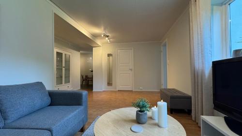 a living room with a blue couch and a table at Romslig leilighet med 2 soverom - GRATIS PARKERING in Tromsø