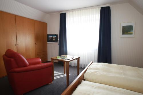 a hotel room with a bed and a chair and a table at Gästehaus Wacholderheide Garni in Eimke