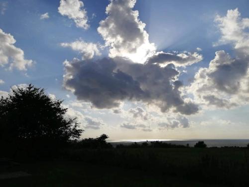 a cloudy sky over a field with the ocean at Seaside Serenity in LumsAYs-By Traum in Ebbeløkke