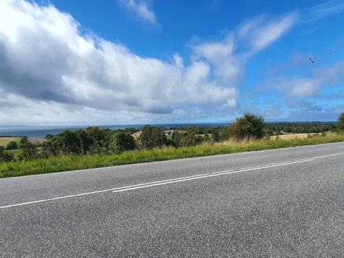 an empty highway with a blue sky and clouds at Seaside Serenity in LumsAYs-By Traum in Ebbeløkke