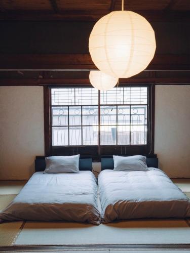 two beds in a room with a window and a chandelier at みんとん家 in Takamatsu