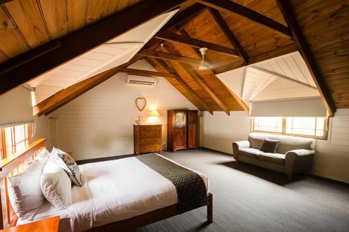 a bedroom with a bed and a couch in a attic at Peppers Creek Accommodation in Pokolbin