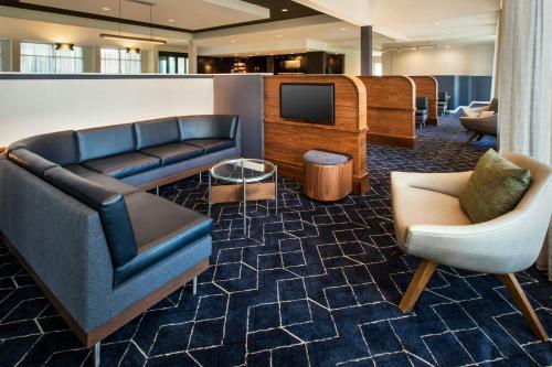 a lobby with a couch and a tv and chairs at Courtyard Philadelphia Devon/Villanova in Wayne
