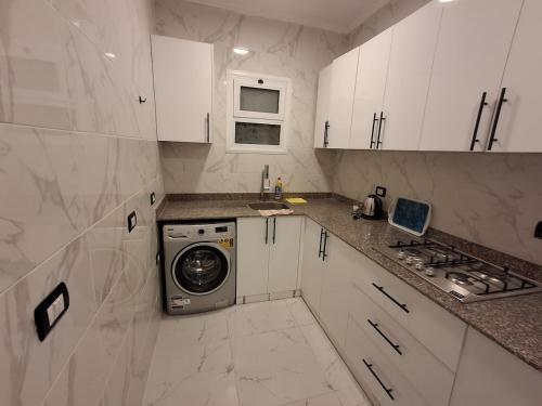 a white kitchen with a washing machine in it at 1 room apartment Delta in Sharm El Sheikh